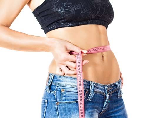 Frau misst ihren Bauchumfang mit Massband